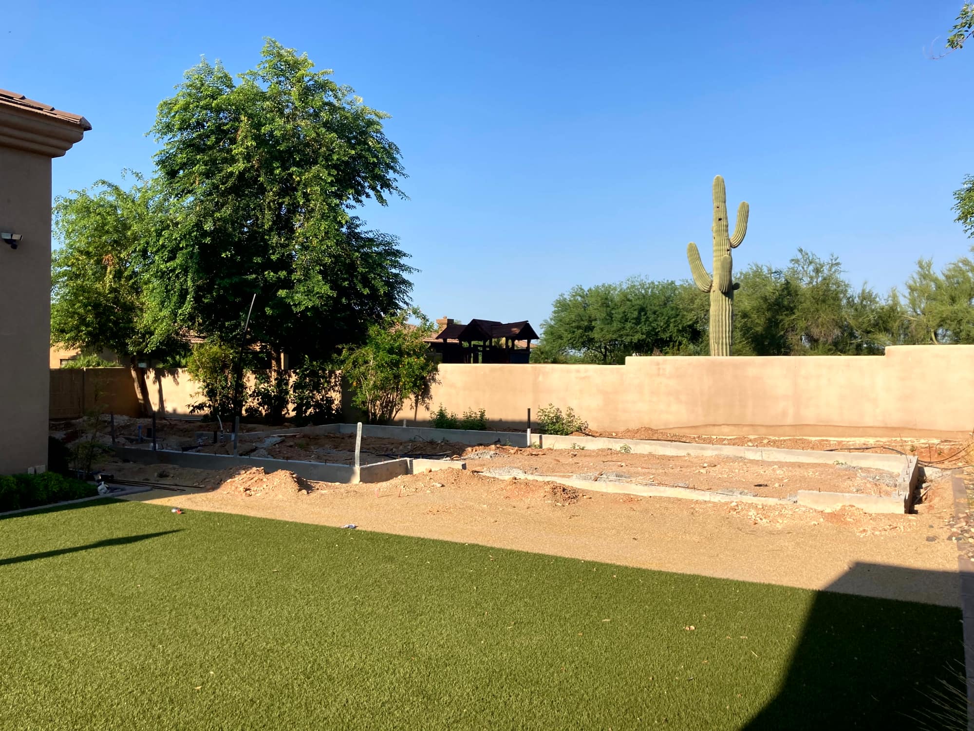 Casita foundation and stem walls in the backyard, with a saguaro beyond the wall