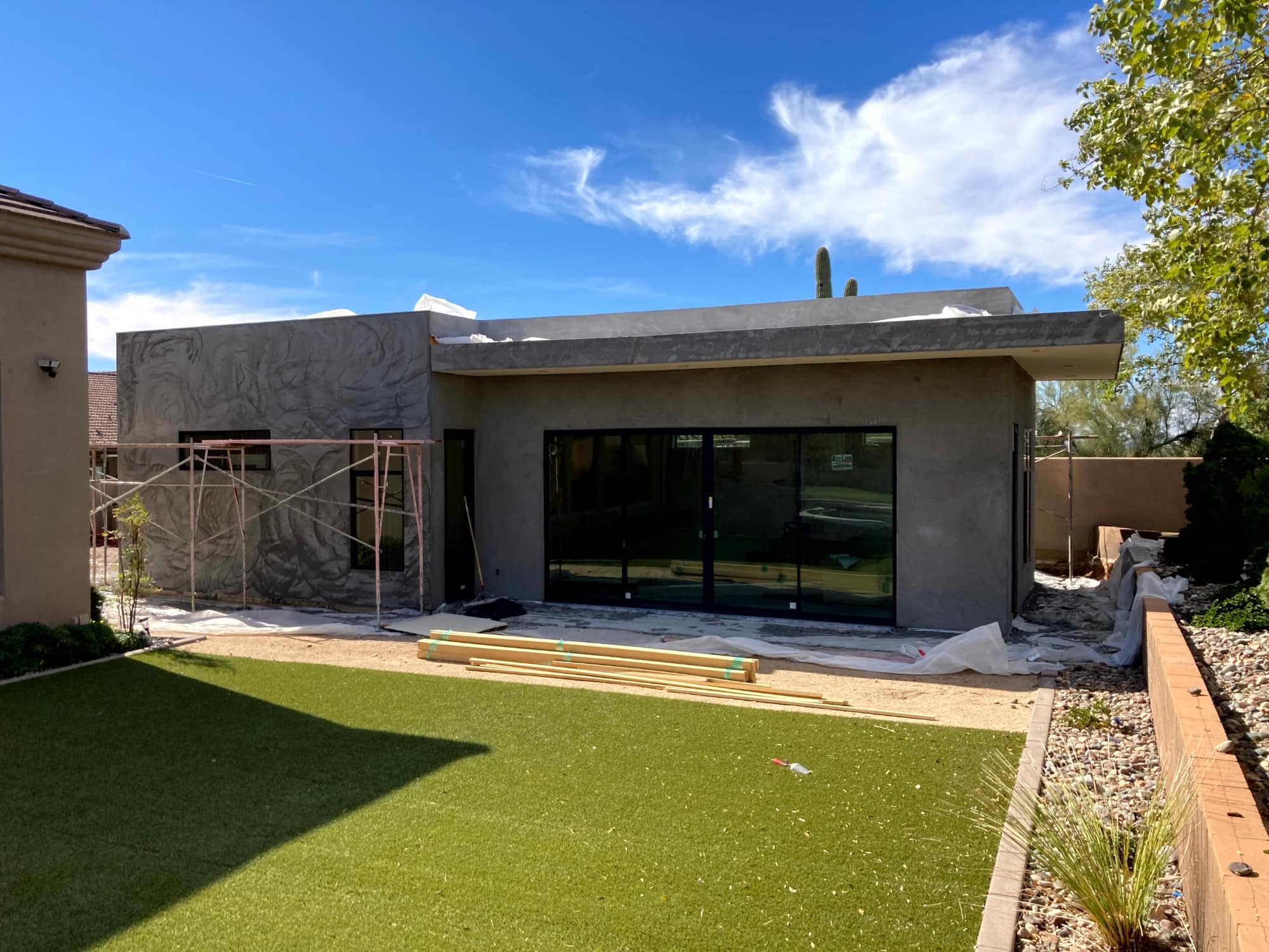 Stucco exterior with black-framed sliding glass doors during construction